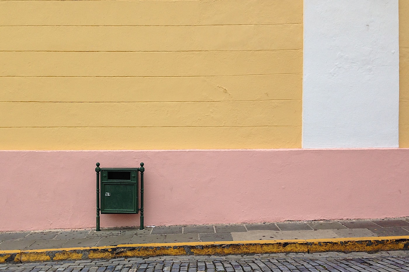 Green mailbox beside a pink wall