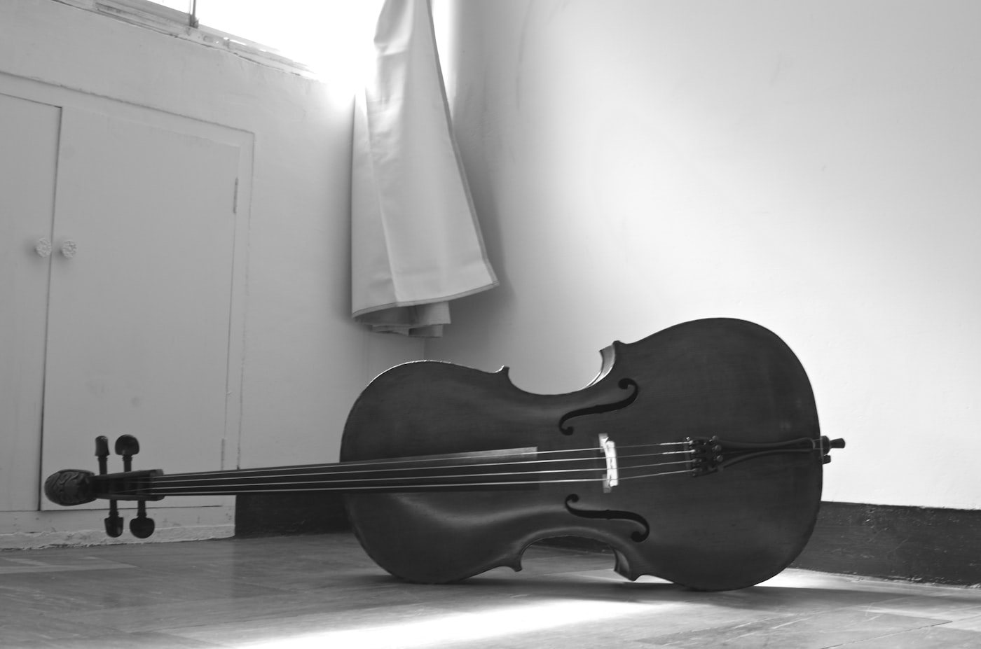 A cello lying on a floor, in black and white