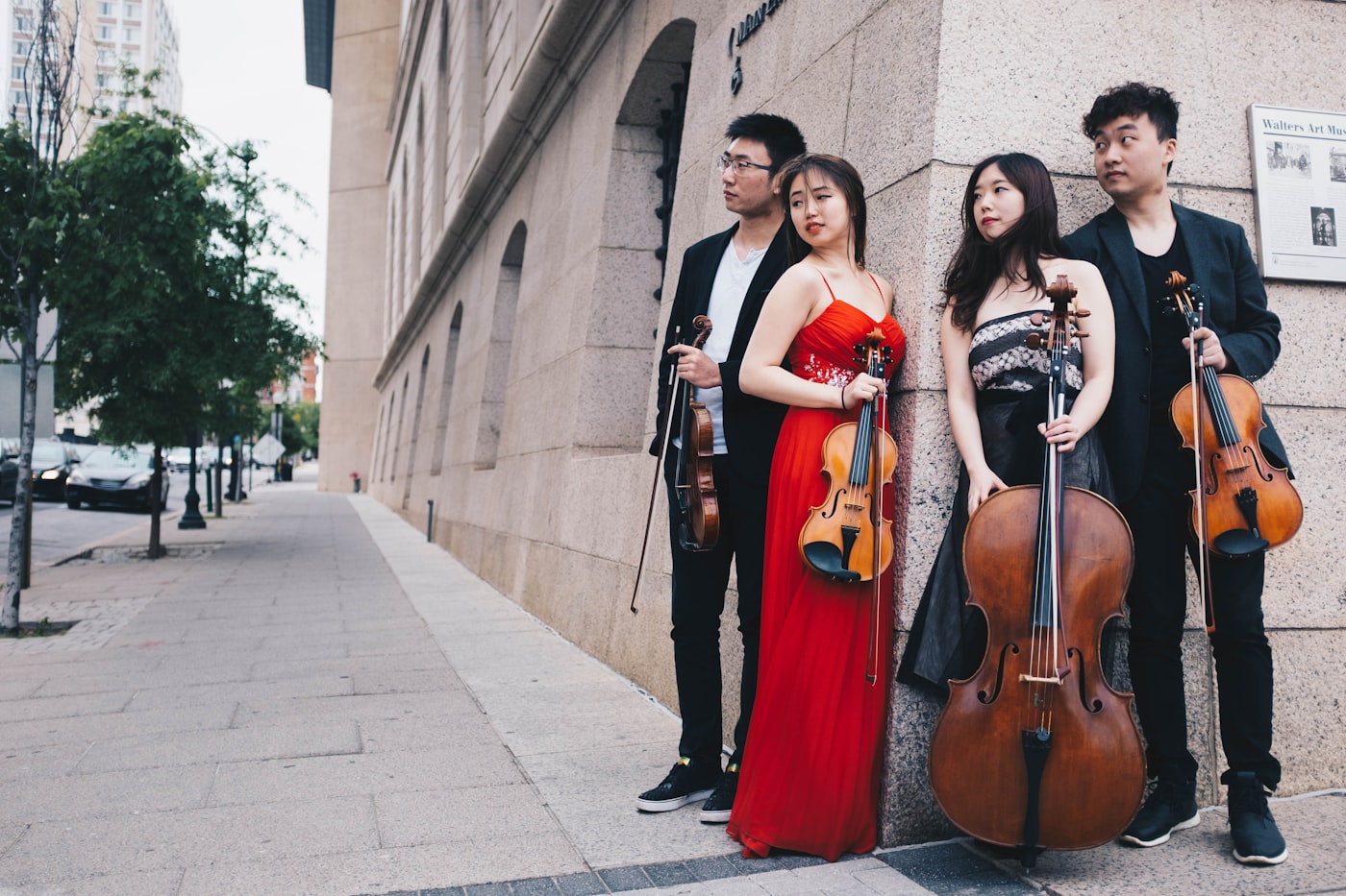 A string quartet posed against a stone museum wall